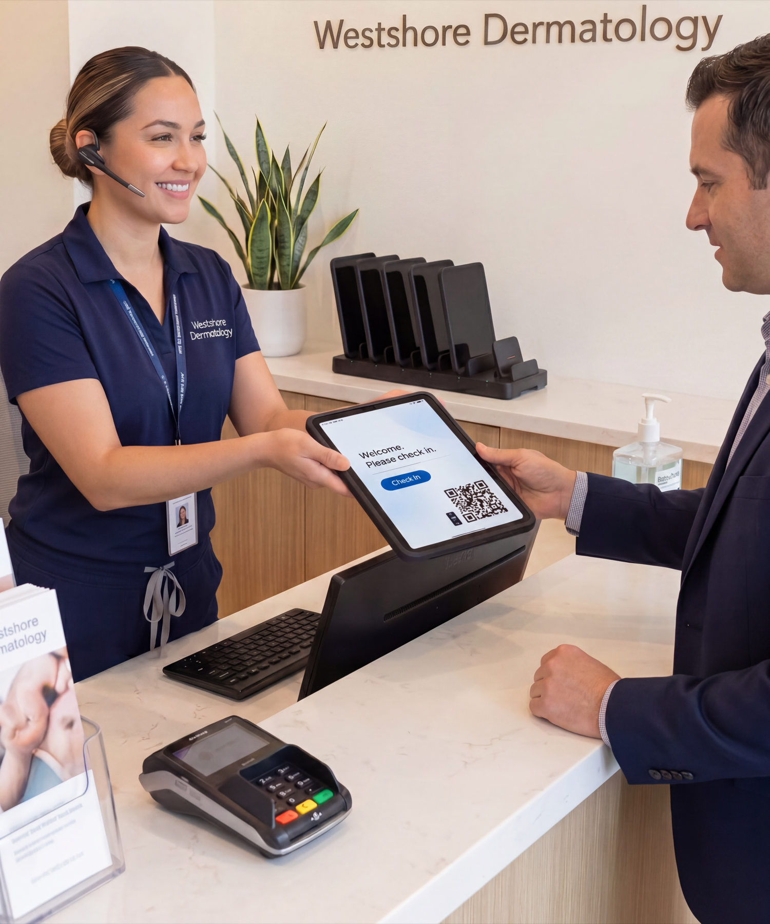 A dermatology receptionist hands a male patient a CONNECT Case iPad showing a check-in screen, with a MultiDock 6 charging station on the Westshore Dermatology front desk